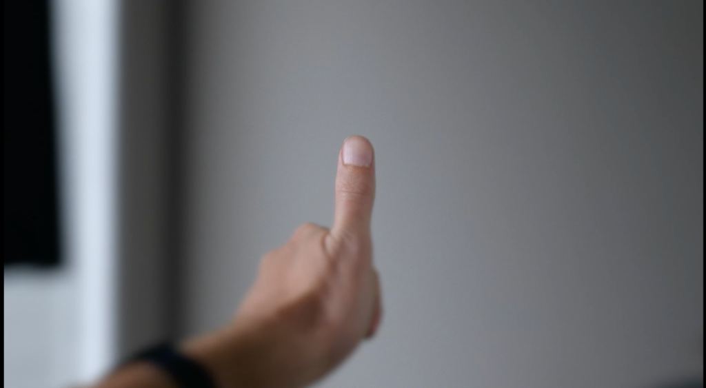 Straight-on color close-up of a white hand giving the thumbs-up gesture in the center of the frame.