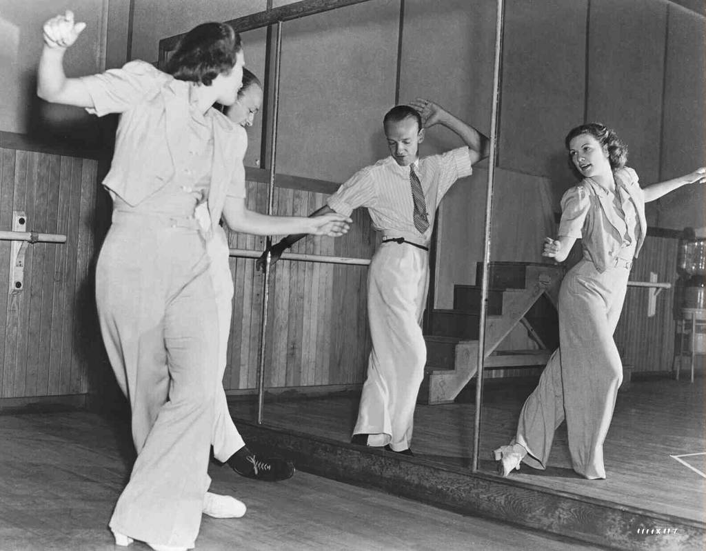 Straight-on black-and-white long shot of Fred Astaire and Eleanor Powell practicing a dance routine in front of a mirror