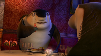 Great white shark, Don Lino (Robert De Niro), at an elegant restaurant with his shark son, Lenny (Jack Black). They sit across from each other as Don Lino frustratedly holds out a shrimp from his shrimp cocktail for Lenny to eat in front of him.