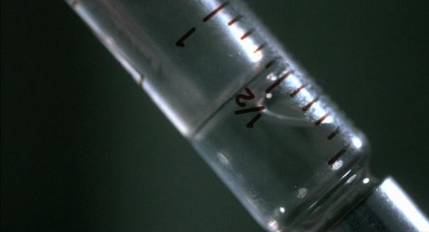 A straight-on color extreme close-up of a syringe with liquid at the 1/2-inch mark