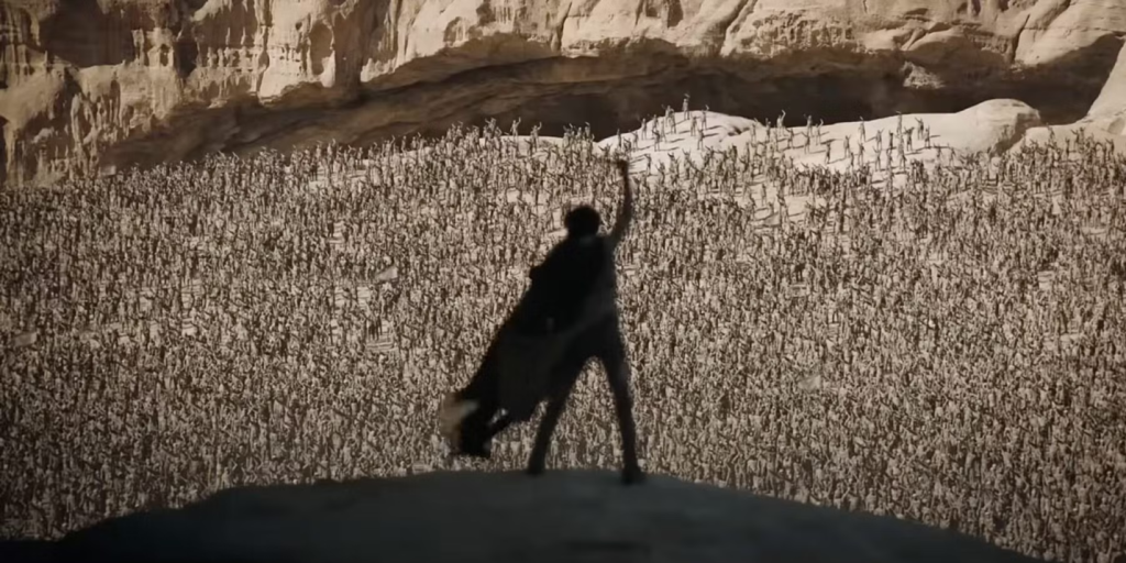 A person standing on a hill with a group of people in the background