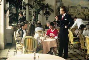 The formally dressed worker waits on Ferris, Cameron, and Sloane who are seated at a table in the restaurant, clearly underdressed and out of place.