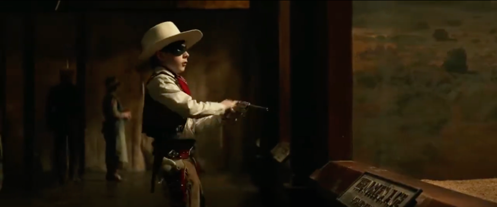 A young boy dressed as the Lone Ranger points a toy gun directly at Tonto in the museum exhibit.